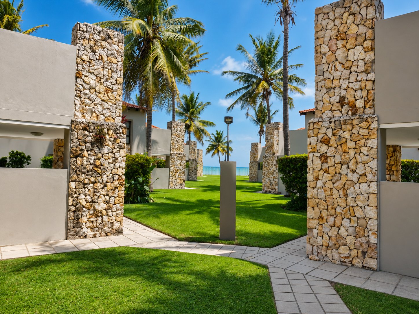 Garden path between stone pillars leading toward the beach